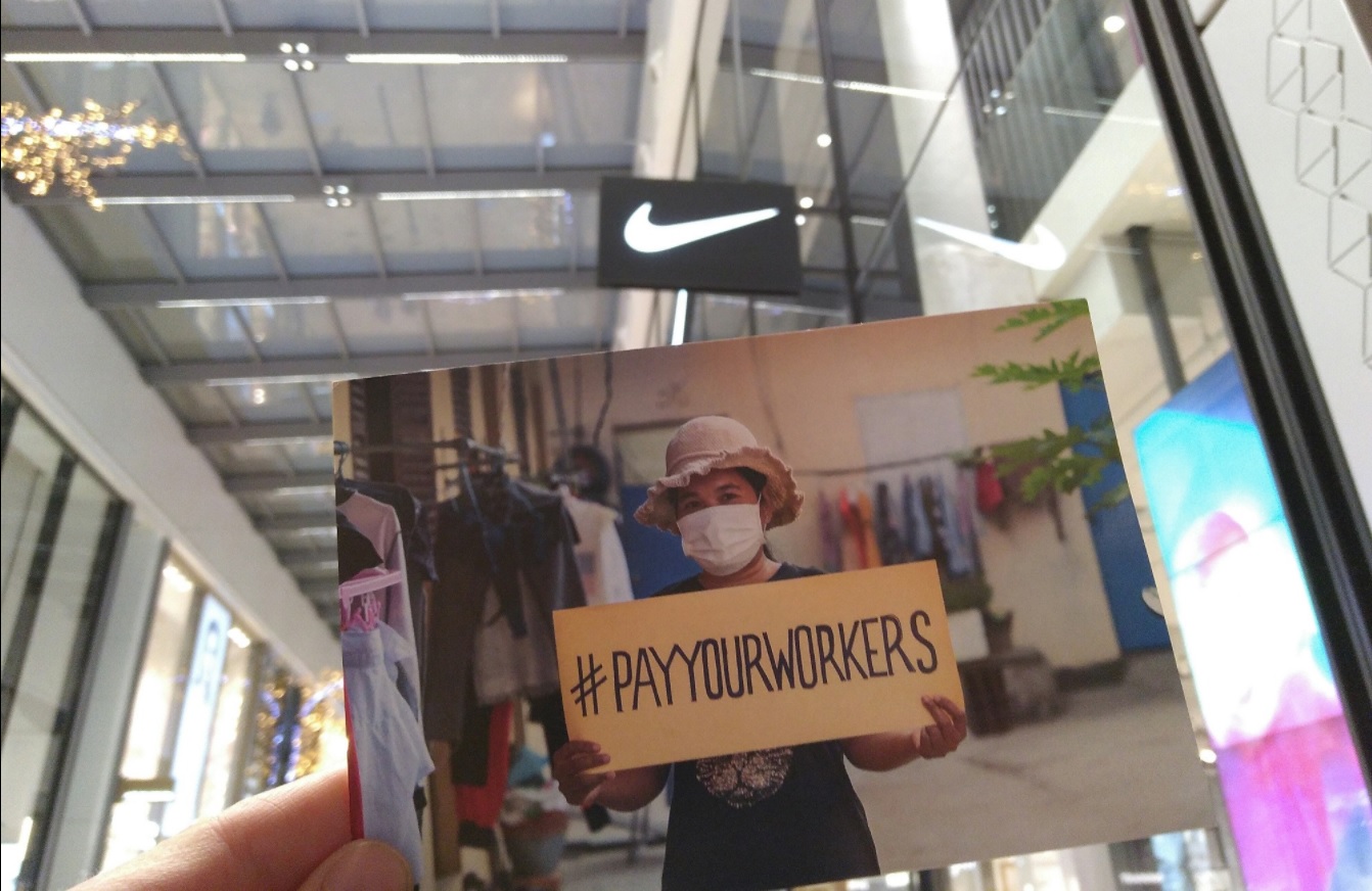 Postal de la campaña Pay Your Workers ante una tienda de NIKE, para exigir a la marca que pague a sus trabajadoras