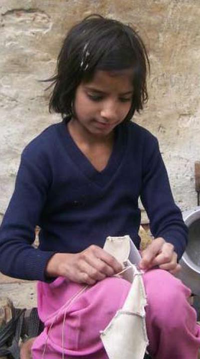 Una niña cosiendo a mano balones de fútbol